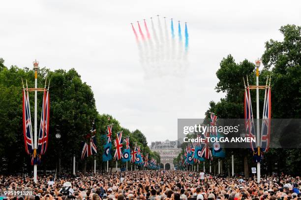 People watch as the The Red Arrows take part in a fly-past over the Mall and Buckingham Palace in London on July 10, 2018 to mark the centenary of...