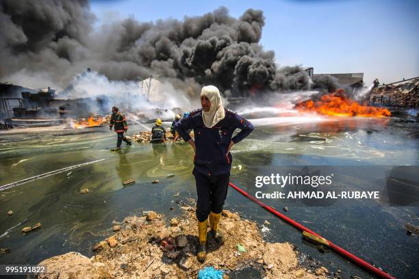 An Iraqi firefighter gazes during a blaze as comrades attempt to put out a fire that broke out due to extreme summer temperatures in a warehouses...