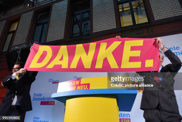 Two men hold up a banner that reads "Danke" at an FDP election party after the first projections on the German election at...