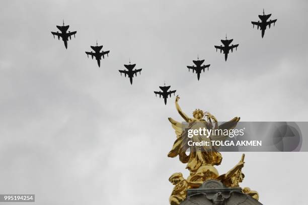 Military aircraft take part in a fly-past over the Queen Victoria Memorial on the Mall outside Buckingham Palace in London on July 10, 2018 to mark...