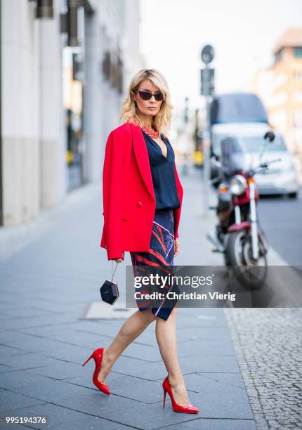 Gitta Banko wearing a red fitted blazer by Steffen Schraut, blue silk blouse with deep V-neck by Bash, red stingray leather oversize necklace by a...