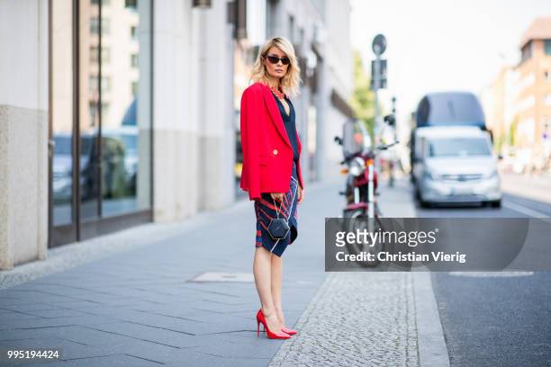 Gitta Banko wearing a red fitted blazer by Steffen Schraut, blue silk blouse with deep V-neck by Bash, red stingray leather oversize necklace by a...