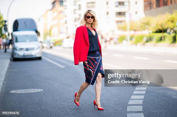 Gitta Banko wearing a red fitted blazer by Steffen Schraut, blue silk blouse with deep V-neck by Bash, red stingray leather oversize necklace by a...