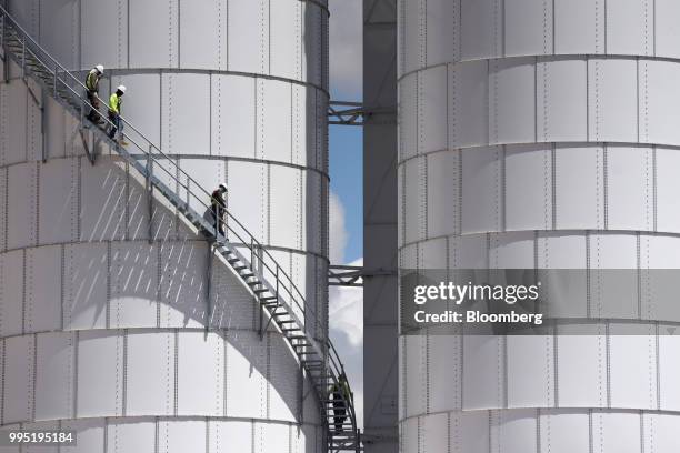 Workers climb down the stairs of a silo at the Hi-Crush Partners LP mining facility in Kermit, Texas, U.S., on Wednesday, June 20, 2018. In the West...