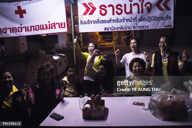 Volunteers celebrate at a makeshift press centre in Mae Sai district of Chiang Rai province on July 10 after the twelve boys and their football coach...