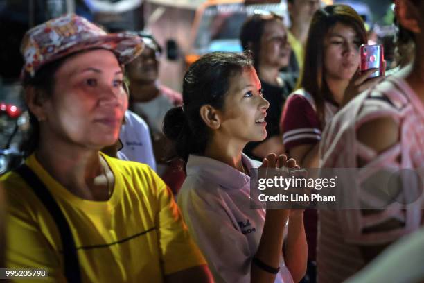 July 10: Onlookers at the junction in front of Chiangrai Prachanukroh Hospital watch and cheer as ambulances transport the last rescued schoolboys &...