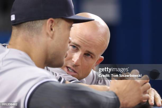 Brett Gardner of the New York Yankees talks to Giancarlo Stanton as they sit on the top step of the dugout during MLB game action against the Toronto...