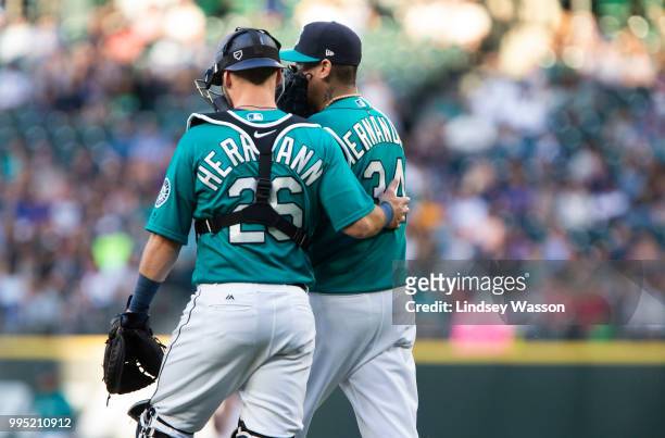 Chris Herrmann of the Seattle Mariners talks with Felix Hernandez on the mound in the third inning against the Colorado Rockies at Safeco Field on...