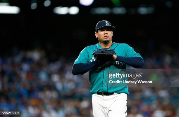 Felix Hernandez of the Seattle Mariners puts his hand in his glove as he walks back to the dugout after pitching five innings against the Colorado...