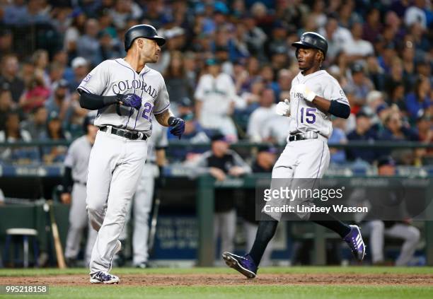 Ian Desmond of the Colorado Rockies looks back at Raimel Tapia as they score on a triple by Tony Wolters in the sixth inning against the Seattle...