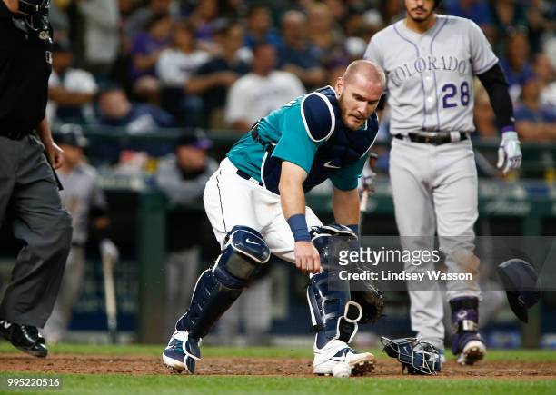 Chris Herrmann of the Seattle Mariners throws off his helmet to grab a pitch in the dirt during the sixth inning against the Colorado Rockies at...