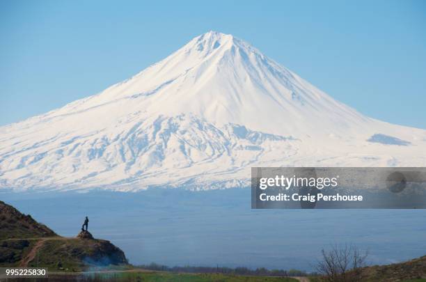 snow-covered mt ararat towers above the countryside and statue of kevuk chavush. - dormant volcano stock-fotos und bilder