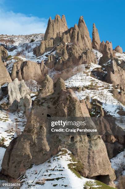 volcanic rock pinnacles and ancient cave dwellings on snow-covered mountain above old goris. - craig pershouse stockfoto's en -beelden