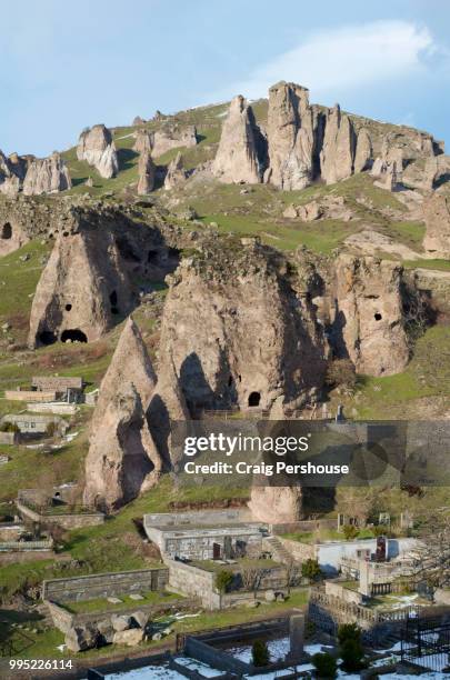 volcanic rock pinnacles with ancient cave dwellings above cemetery in old goris. - craig pershouse stockfoto's en -beelden