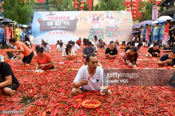 Challengers sit in a chili-covered pool eat chilies during a chili-eating contest on July 8, 2018 in Ningxiang, Hunan Province of China. Citizen Tang...