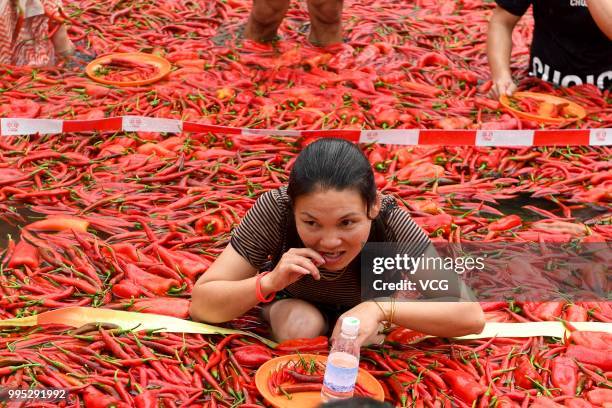 Challengers sit in a chili-covered pool eat chilies during a chili-eating contest on July 8, 2018 in Ningxiang, Hunan Province of China. Citizen Tang...