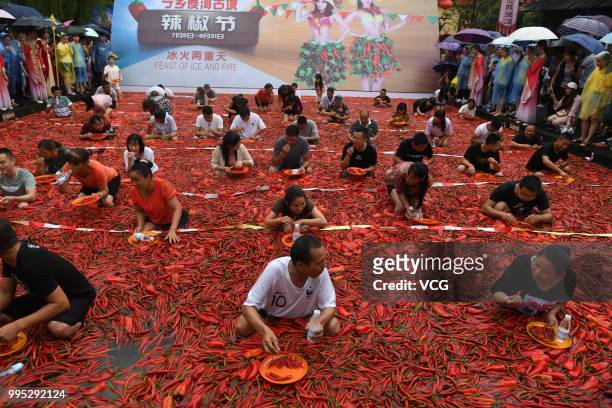 Challengers standing in a chili-covered pool eat chilies during a chili-eating contest on July 8, 2018 in Ningxiang, Hunan Province of China. Citizen...
