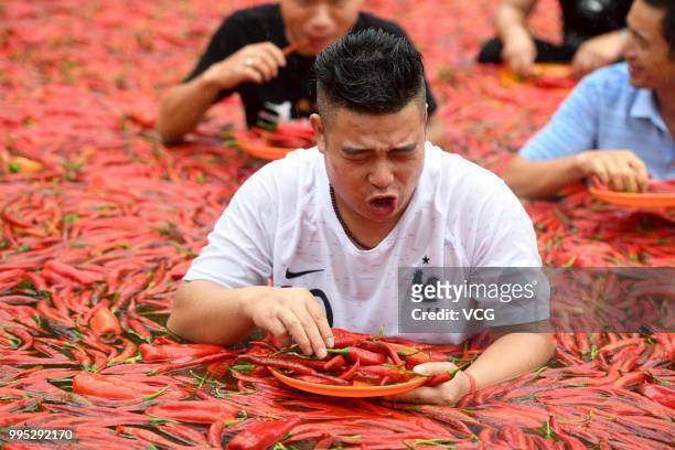 Challengers standing in a chili-covered pool eat chilies during a chili-eating contest on July 8, 2018 in Ningxiang, Hunan Province of China. Citizen...