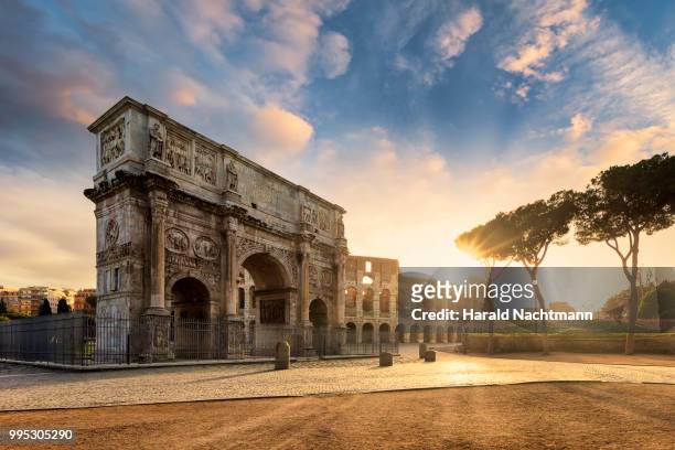 arch of constantine with the colosseum in the background at sunrise, rome, lazio, italy - rom stock-fotos und bilder