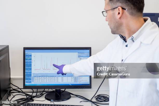 scientist pointing at graph on computer monitor - computer scientist stock pictures, royalty-free photos & images