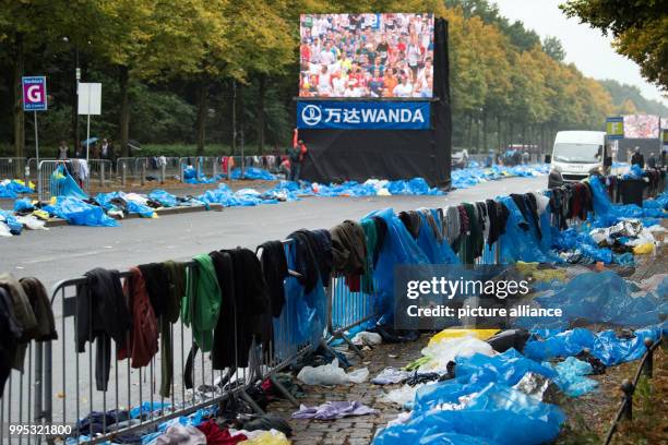 Blue plastic folio and the jackets and sports clothing of athletes cover the side of the street during the 44th Berlin Marathon in Berlin, Germany,...