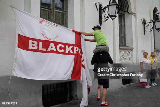 Russian women look on as England fans hoist their flag in Nikolskaya St near Red Square ahead of the World Cup semi-final game between England and...