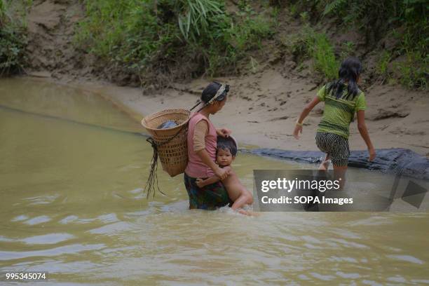 Reang women with a kid is seen in a stream with dirty water. 35,000 people of Reang also called Bru in Kanchanpur refugee camp, fled here due to...