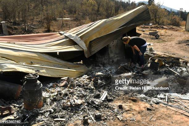 Michelle West sifts through the ashes of what is left of her family's home at the bottom of La Veta Pass on July 9, 2018 in La Veta, Colorado. The...