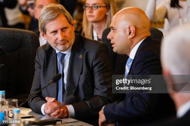 Johannes Hahn, European commissioner, left, speaks with Sajid Javid, U.K. Home secretary, during a plenary session at the Western Balkans Summit 2018...