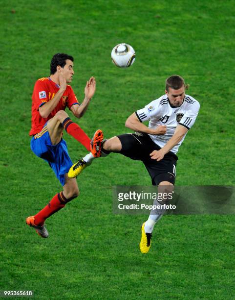 Lukas Podolski of Germany and Sergio Busquets of Spain battle for the ball during the FIFA World Cup Semi Final at the Moses Mabhida Stadium on July...