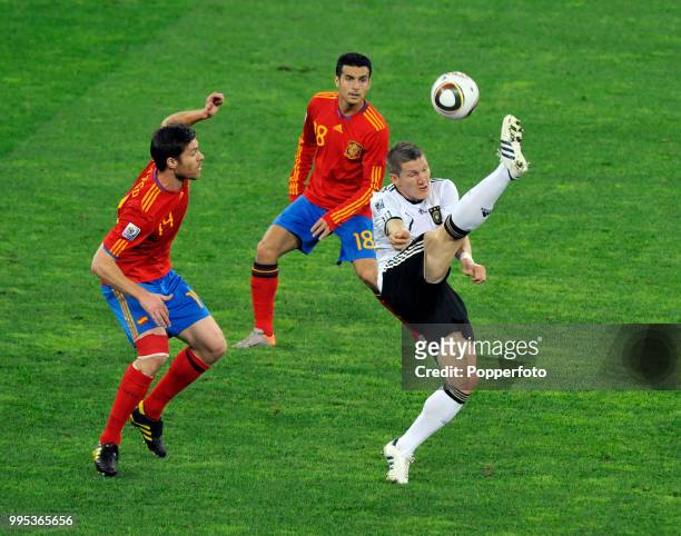 Bastian Schweinsteiger of Germany under pressure from Xabi Alonso and Pedro of Spain during the FIFA World Cup Semi Final at the Moses Mabhida...