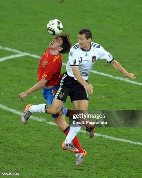 Miroslav Klose of Germany battles with Carlos Puyol of Spain during the FIFA World Cup Semi Final at the Moses Mabhida Stadium on July 7, 2010 in...