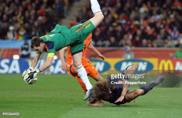 Iker Casillas of Spain collides with teammate Carlos Puyol as he collects the ball under pressure from Robin van Persie of the Netherlands during the...