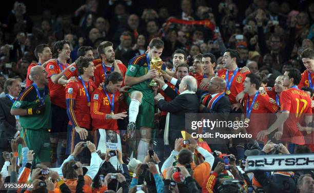 Iker Casillas of Spain receives the trophy from FIFA President Sepp Blatter after the FIFA World Cup Final between the Netherlands and Spain on July...