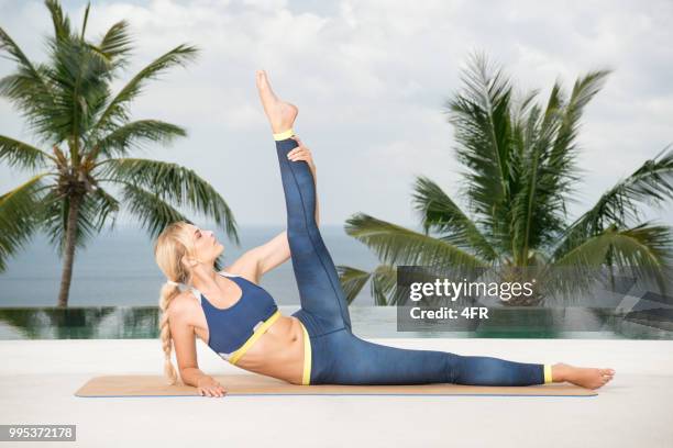 athletic woman working out, stretching in front of a beautiful tropical background on vacation - revolved triangle pose stock pictures, royalty-free photos & images