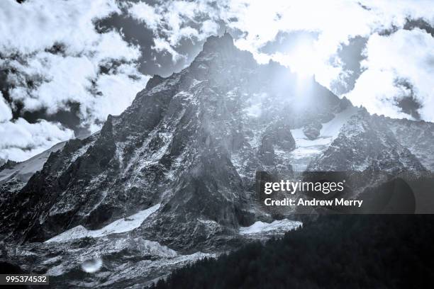 aiguille du midi summit, peak, mountain range back lit by sun and clouds - midirock stock pictures, royalty-free photos & images