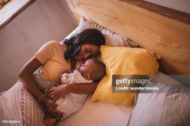 young mother embracing baby boy and sleeping in bed - 12 23 months stock pictures, royalty-free photos & images