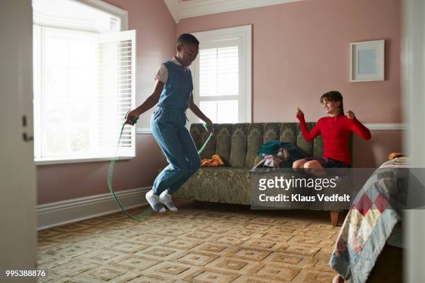 girl skipping at home, while friend is cheering - girls in socks stockfoto's en -beelden