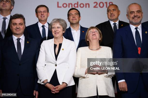 Germany's Chancellor Angela Merkel looks at the ceiling next to Britain's Prime Minister Theresa May as they prepare for a family photo during the...