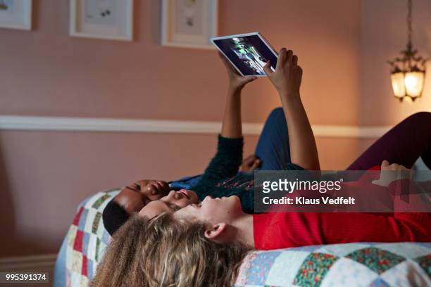 friends laying in bed and looking at tablet with pictures - girl upside down stock pictures, royalty-free photos & images