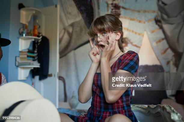 girl sitting on bed making funny face while trying glasses - girl open mouth bildbanksfoton och bilder
