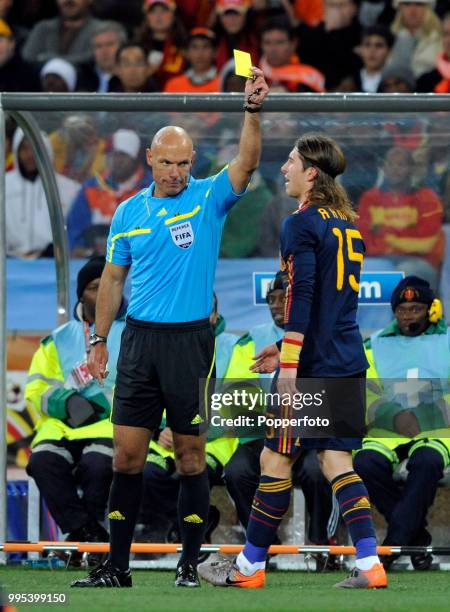 Referee Howard Webb shows the yellow card to Sergio Ramos of Spain during the FIFA World Cup Final between the Netherlands and Spain at the Soccer...