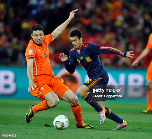 Mark van Bommel of the Netherlands attempts to tackle Pedro of Spain during the FIFA World Cup Final at the Soccer City Stadium on July 11, 2010 in...