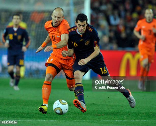 Arjen Robben of the Netherlands is challenged by Sergio Busquets of Spain during the FIFA World Cup Final at the Soccer City Stadium on July 11, 2010...
