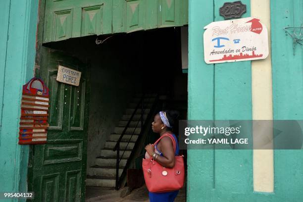 Woman stands next to a house with a sign advertising a private room for rent in Havana, on June 10, 2018. Cuba gave Tuesday a new green light to...