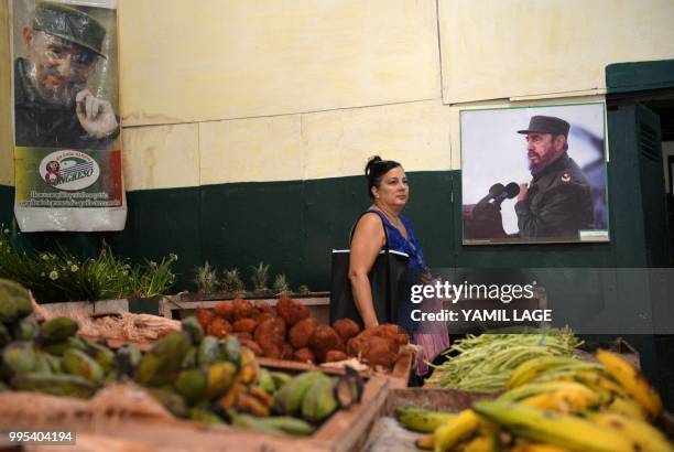 Woman shops for vegetables next to poster of Cuban late leader Fidel Castro at a market in Havana, on June 10, 2018. - Cuba gave Tuesday a new green...
