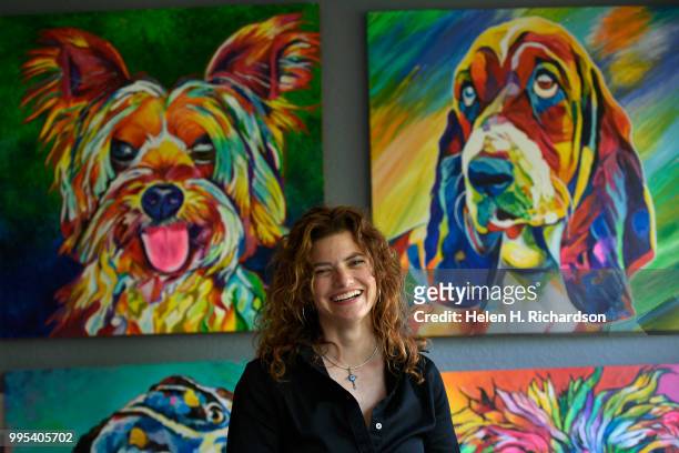 Artist Tif Choate sits for a portrait in front of some of her dog paintings in her home studio on July 1, 2018 in Lafayette, Colorado. The smallest...