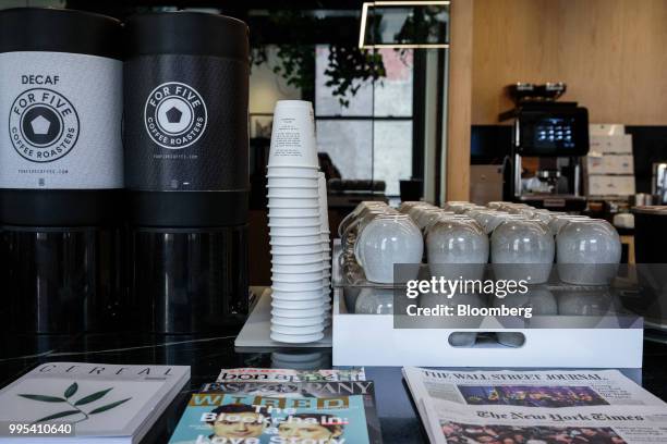 Newspapers and magazines sit on display in front of a coffee station at the Convene workspace flagship location in New York, U.S., on Monday, July 2,...