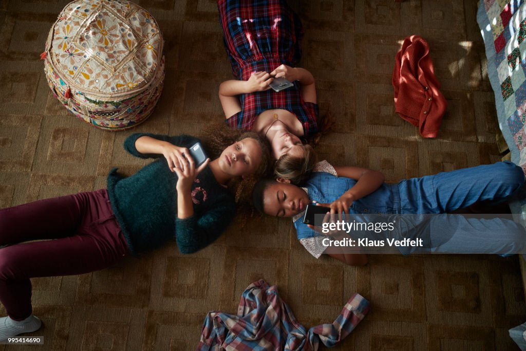 Top view of 3 tween girls looking at their smartphones