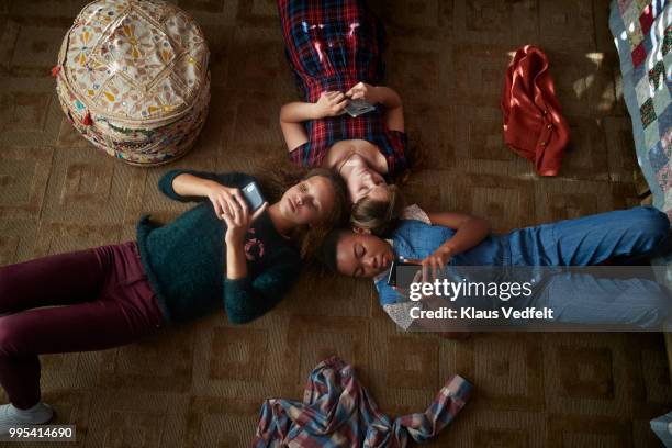 top view of 3 tween girls looking at their smartphones - carpet mess stock pictures, royalty-free photos & images